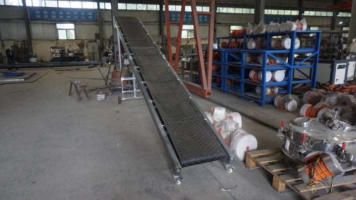 Foldable belt conveyor system transporting cardboard boxes in a warehouse facility
