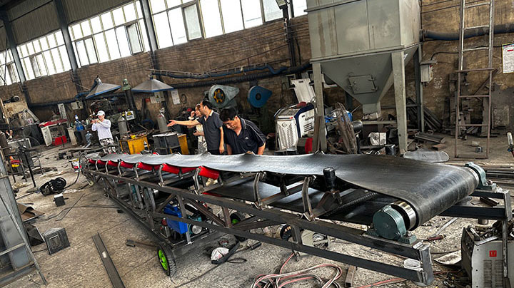 Custom hydraulic-lifting belt conveyor undergoing pre-shipment testing in the factory for silica sand handling.
